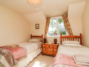 two beds in a room with a window at Ash Tree Cottage in Holsworthy