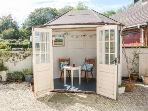 a white shed with a table and chairs in it at Ash Tree Cottage in Holsworthy