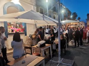 una multitud de personas sentadas en las mesas fuera de un restaurante en Loft Sul Mare, en Balestrate