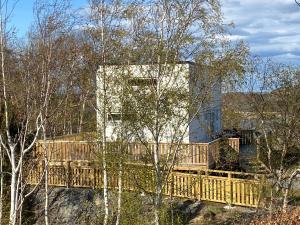 Mycket trevlig stuga på Brännö med havsutsikt في Brännö: منزل مع جسر خشبي في الغابة