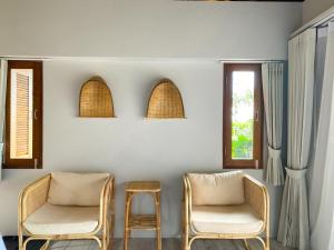 two chairs and a stool in a room with windows at The Mak Trat in Ko Mak