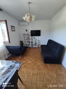 a living room with two blue chairs and a television at Bruna's apartment in Vrulje