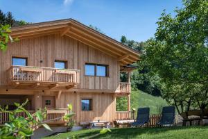 a log home with a deck and chairs in the yard at Gschlunerhof in Castelrotto