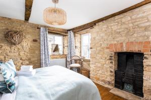1 dormitorio con pared de ladrillo, cama y chimenea en Windsor Cottage - Bolthole in the heart of CN!, en Chipping Norton