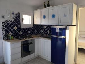 uma cozinha com um frigorífico azul e armários brancos em Bados affaccio sul mare em Olbia