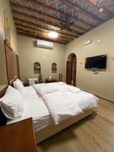 a bedroom with a large bed and a flat screen tv at Nizwa Heritage Inn in Nizwa