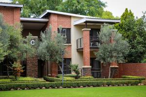 a red brick house with trees in front of it at Scott's Manor Guesthouse Function and Conference Venue in Lichtenburg