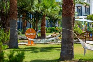 a park with hammocks and palm trees with a dance sign at CHARM BEACH HOTEL in Akyarlar