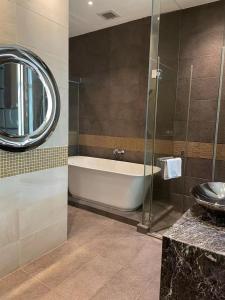 bagno con vasca, lavandino e specchio di Crafa Harbour Hotel a Hong Kong