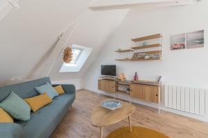 a living room with a blue couch and a desk at Charmant appartement proche centre-ville plage in Saint-Nazaire