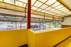 an empty room with yellow walls and a large window at SPOT ON 91159 Kost Putrana Syariah in Cilimus 2