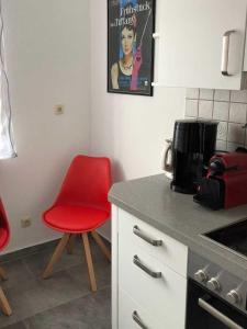 a kitchen with a red chair and a counter at Ferienhaus Meeresleuchten, frisch renoviertes & gemütliches in Hooksiel