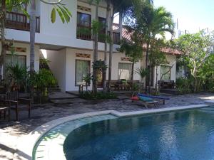 a hotel with a swimming pool in front of a building at family house hotel kuta in Kuta Lombok