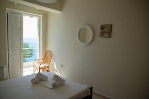 AvíaにあるPalaiohora Avias Apartmentsの白い部屋で、ベッド1台(鏡付)、窓が備わります。