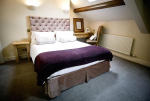 ein Schlafzimmer mit einem großen Bett mit einer lila Decke in der Unterkunft The Waddington Arms in Waddington