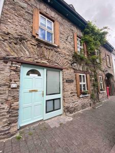a stone building with a blue door and windows at Mariners Rest One Bedroom Apartment in Innishannon Village in Cork
