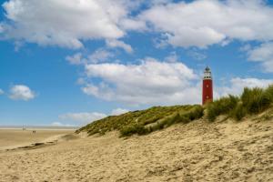 a red lighthouse sitting on top of a sandy beach at EuroParcs Texel in De Cocksdorp +8 photos