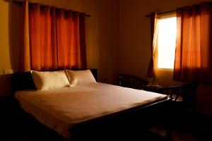 Schlafzimmer mit einem Bett mit orangefarbenen Vorhängen und einem Fenster in der Unterkunft Biosphere in Coonoor