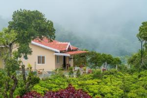 a house in the middle of a field of plants at Biosphere in Coonoor