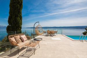 un patio con mesa y sillas y vistas al agua en Beachfront Holiday Home - Private Heated Pool, en Mimice