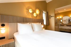 - une chambre avec un grand lit blanc et un miroir dans l'établissement Boutique Hotel Helder I Kloeg Collection, à Renesse