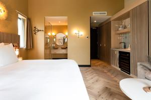 a bedroom with a large white bed and a bathroom at Boutique Hotel Helder I Kloeg Collection in Renesse