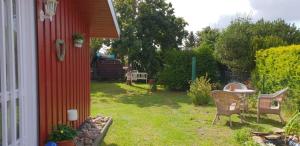 a yard with a red house with a table and chairs at Ferienhaus Treeneglück in Silberstedt