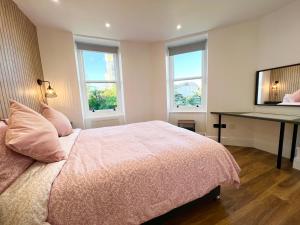 a bedroom with a bed with a desk and two windows at Lovely Apartment, One Minute from Bournemouth Beach and Town. in Bournemouth