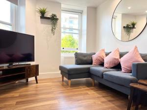 a living room with a blue couch and a flat screen tv at Lovely Apartment, One Minute from Bournemouth Beach and Town. in Bournemouth
