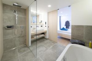 een badkamer met een douche, een wastafel en een bad bij Alpin Chalet Trinkl in Bad Wiessee