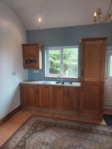 une cuisine avec des placards en bois et une fenêtre dans l'établissement Two bed bungalow with sunroom and stunning views, à Killybegs