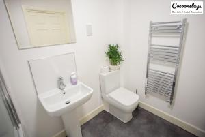 Baño blanco con aseo y lavamanos en Cocooonstays Stays Short Lets & Serviced Accommodation Slough, en Slough