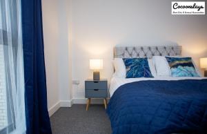a bedroom with a bed and a lamp on a night stand at Cocooonstays Stays Short Lets & Serviced Accommodation Slough in Slough