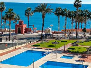 a resort with a pool and palm trees and the ocean at Benalmadena ALOHA PLAYA SEA VIEW LOFT in Benalmádena