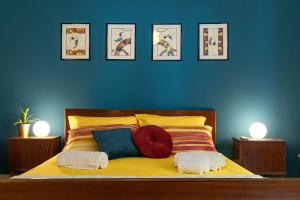 1 dormitorio con 1 cama amarilla con 3 cuadros en la pared en Casa vacanze con giardino - Twiggy's House, en SantʼAntìoco