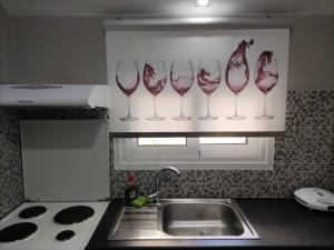 uma cozinha com copos de vinho numa prateleira acima de um lavatório em Wine Reflections Apartment near Nafplio em Néa Kíos