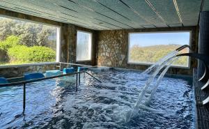 a swimming pool with a waterfall in a room with windows at Hotel Balneario Fuentes del Trampal in Carmonita