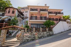 a large pink building with a stone wall at Golden Sun in Agios Ioannis Pelio