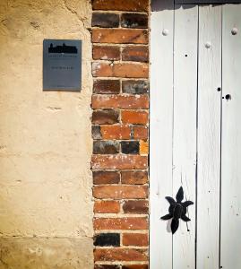 a brick wall with a door with a sign on it at Le Petit Château in Baye