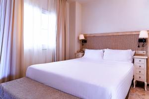 Un dormitorio con una gran cama blanca y una ventana en Aparthotel Cordial Mijas Golf, en Mijas