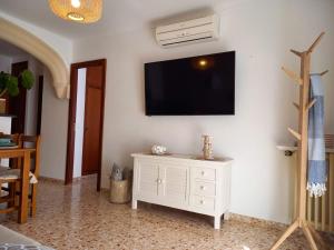 a living room with a white cabinet and a tv on a wall at Hotel Nou Can Guillem in Cala Figuera
