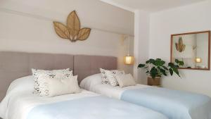 two white beds in a room with a butterfly on the wall at Hotel Nou Can Guillem in Cala Figuera