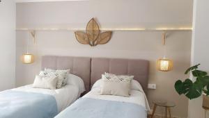two beds in a room with a butterfly on the wall at Hotel Nou Can Guillem in Cala Figuera
