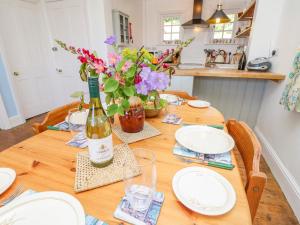 a wooden table with a bottle of wine and flowers at Ladylands Cottage in Newport