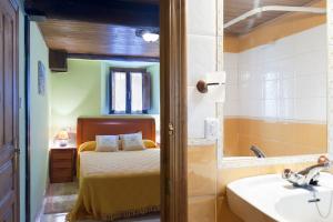 1 dormitorio con cama, bañera y lavamanos en Apartamentos Casa Margot, en Sevares