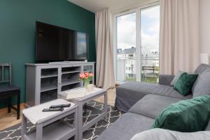sala de estar con sofá y TV de pantalla plana en Apartment Mistral Gdynia with Parking by Renters, en Gdynia