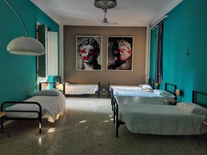 a blue room with two beds and portraits of a woman at Ostello Tasso in Florence