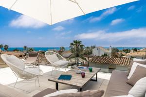 eine Terrasse mit Stühlen, einem Tisch und einem Sonnenschirm in der Unterkunft All About Villa Gladiolo in Marbella + 16 Fotos