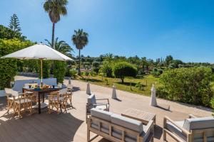 um pátio com uma mesa, cadeiras e um guarda-sol em Quinta das Castelhanas, Jardim Relvado, Piscina, Padel e Golf privados! em Portimão