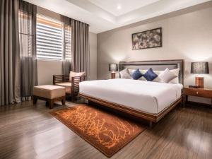 a bedroom with a bed and a chair and a table at Grand Mercure Bangkok Asoke Residence in Bangkok